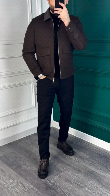 Man wearing a dark brown zip jacket, black top, black trousers and dark leather shoes