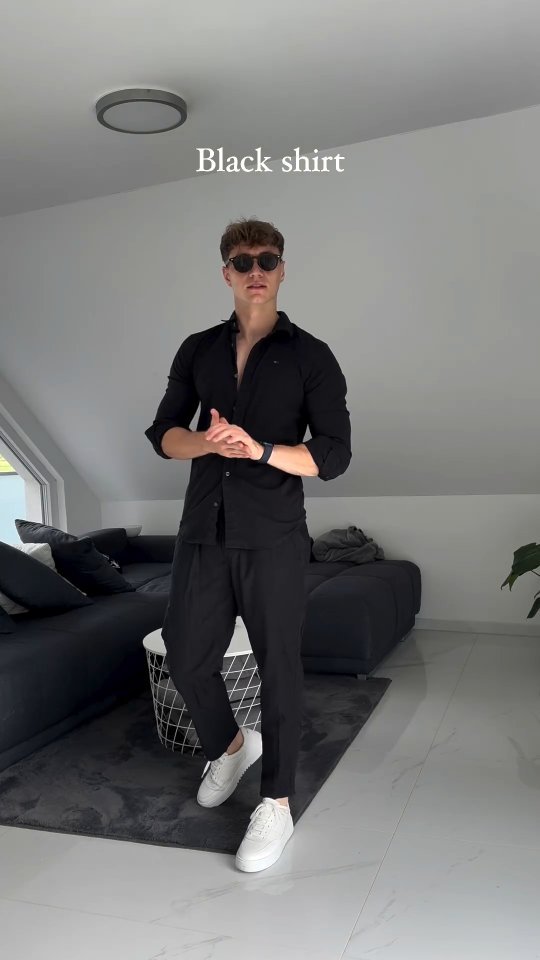 Man wearing a black button-up shirt, black trousers and clean white sneakers