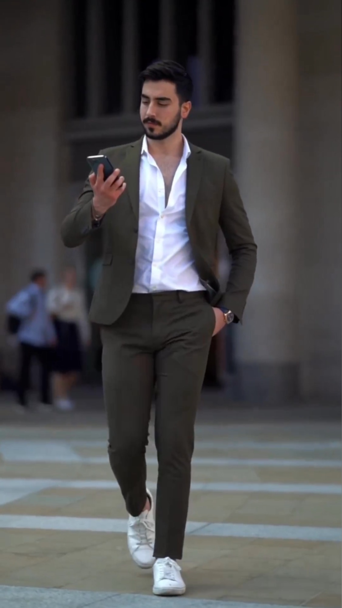 Man wearing an olive green suit, white open-collar shirt and clean white sneakers