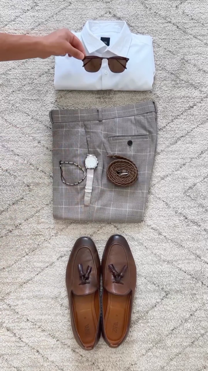 White shirt, light check trousers, brown tassel loafers, braided belt and watch arranged as a men's smart casual outfit