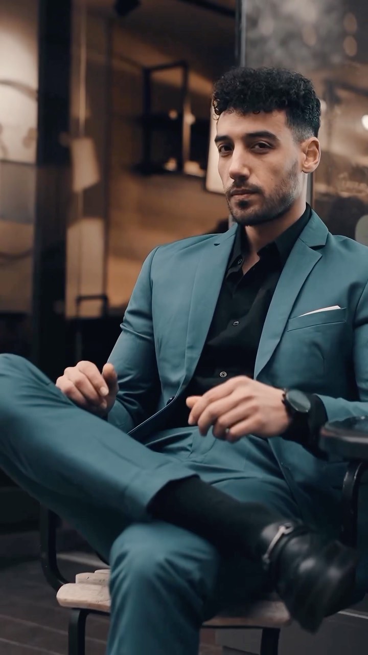 Man wearing a teal suit with a black shirt and black leather loafers