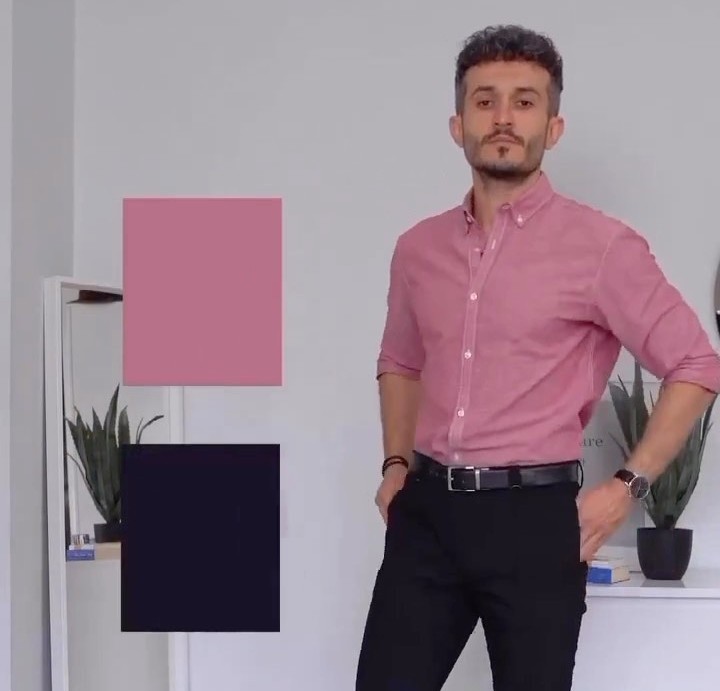 Close view of a dusty pink shirt tucked into black trousers with a black leather belt and silver buckle, sleeves rolled to mid-forearm