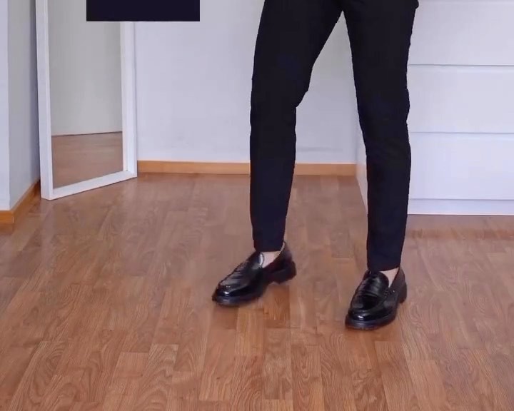 Lower body view showing slim black trousers with a clean no-break hem sitting at the top of black leather loafers worn without visible socks