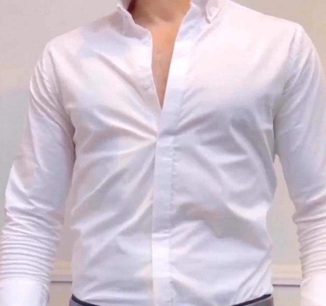 Close view of a clean white button-up shirt with open collar and sleeves gathered neatly at the forearms