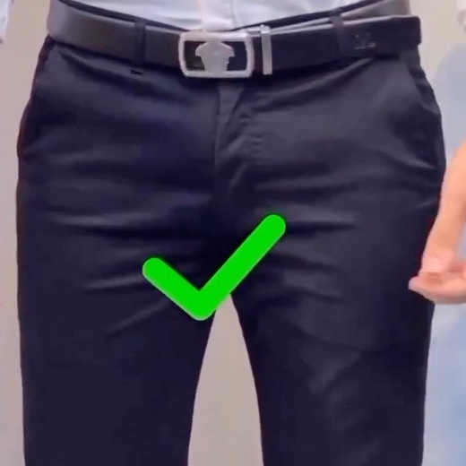 Waist-level view of a tucked white shirt, dark trousers, black belt and green check graphic
