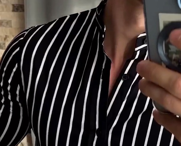 Close view of an open band collar on a black shirt with bold white vertical stripes
