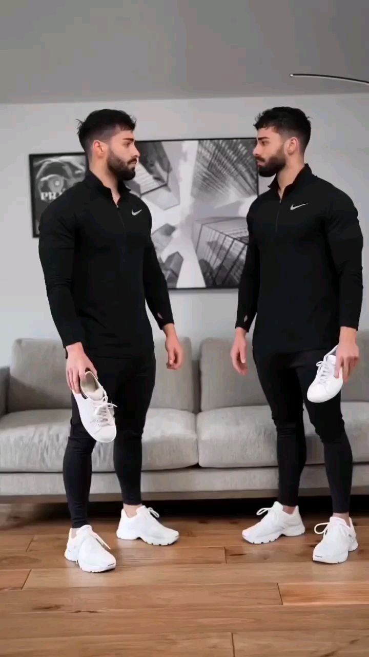 Two men in matching black casual outfits comparing white athletic sneakers with low-profile white sneakers