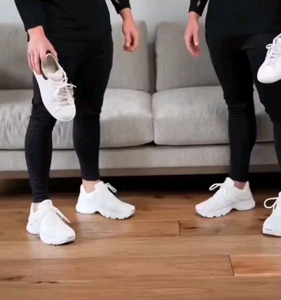 Close comparison of slim black trousers, chunky white athletic sneakers and low-profile white shoes held nearby