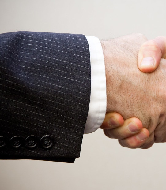 Suit sleeve and white cuff leading into a clean single-handed greeting