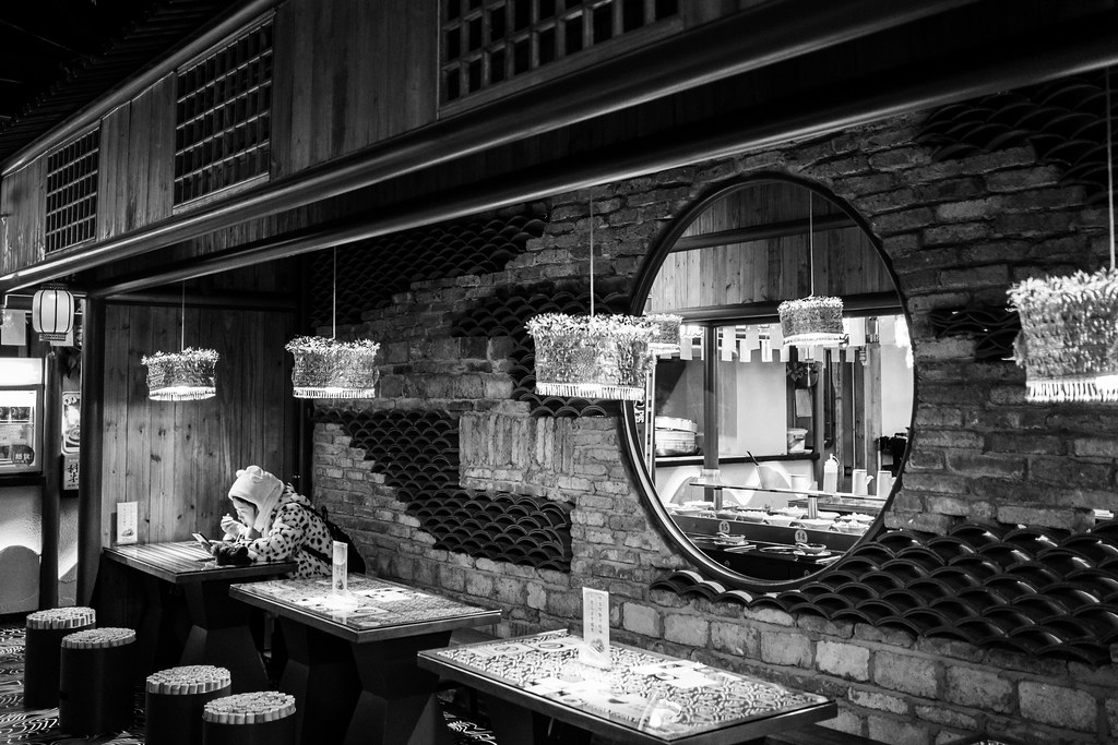 A restaurant interior with a seated patron looking toward a small illuminated phone