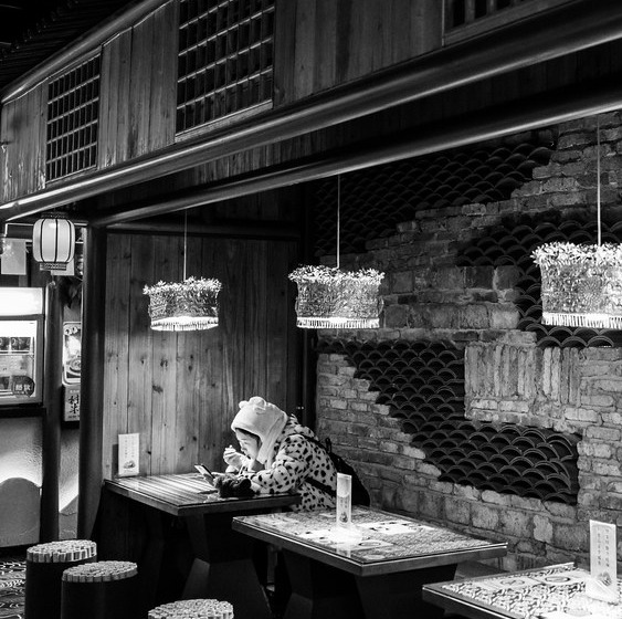 Closer view of a seated restaurant patron looking down toward an illuminated device