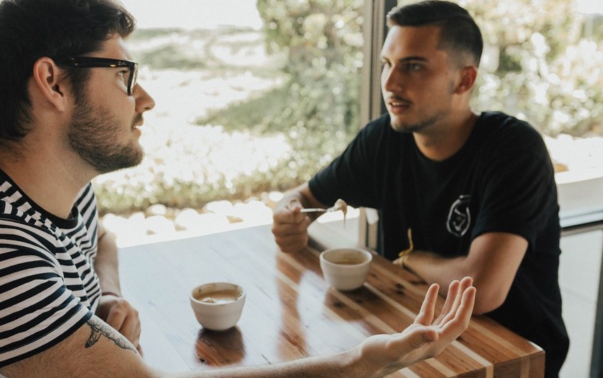 Closer view of two people talking with an open-hand gesture between them