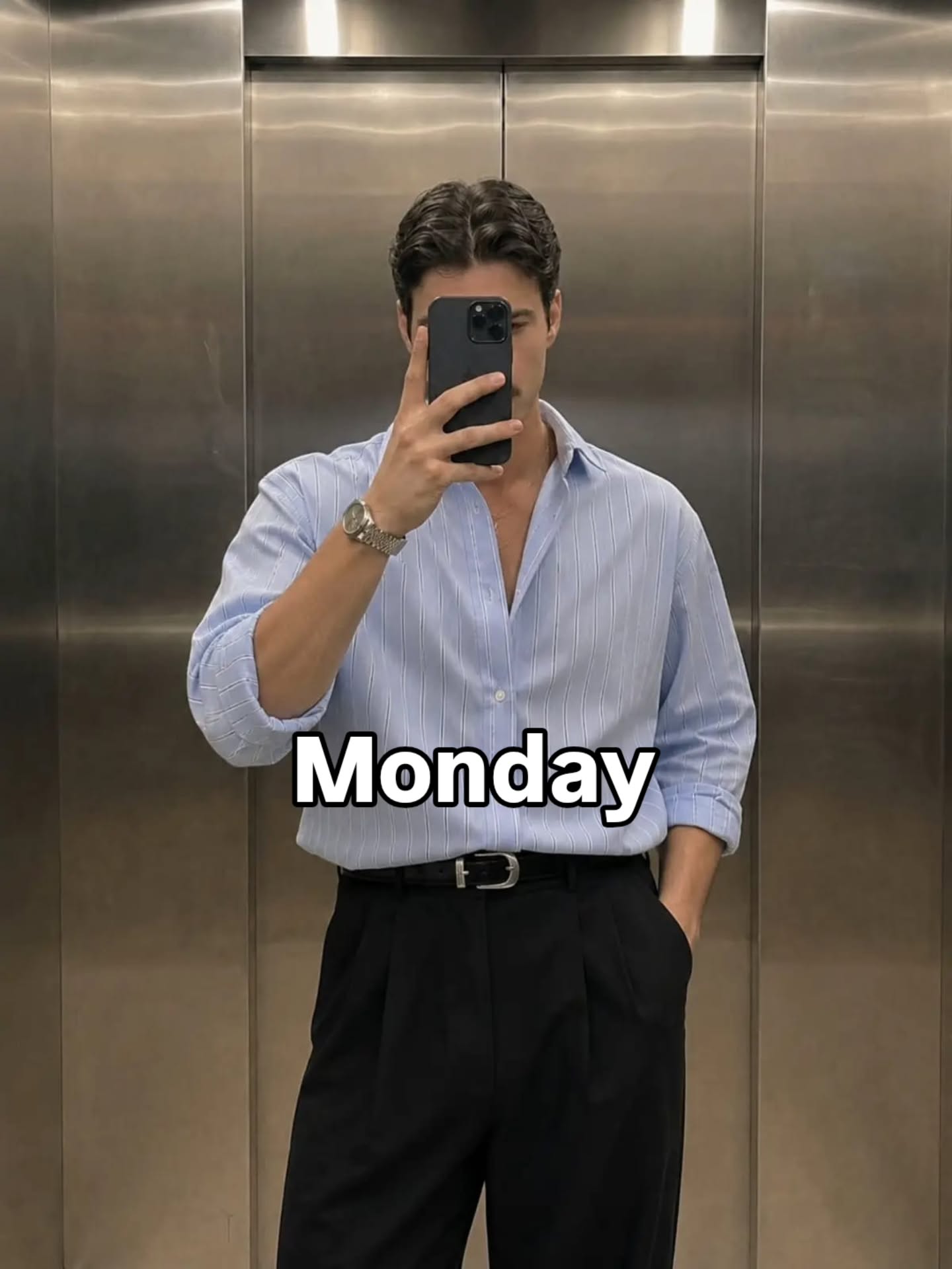 Light blue button-up shirt tucked into black high-waisted pleated trousers with a thin black belt and a silver watch