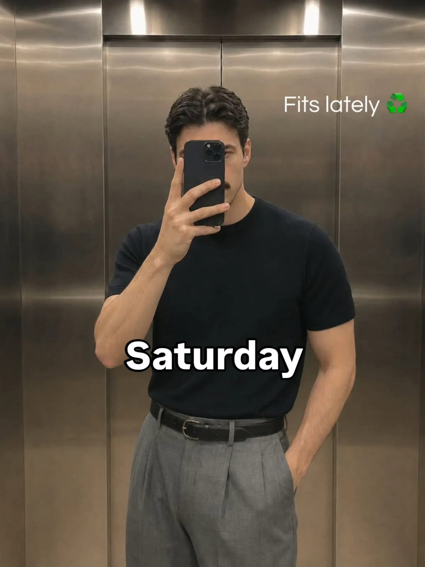 Plain black short-sleeve t-shirt tucked into mid-grey high-waisted pleated trousers with a thin black belt