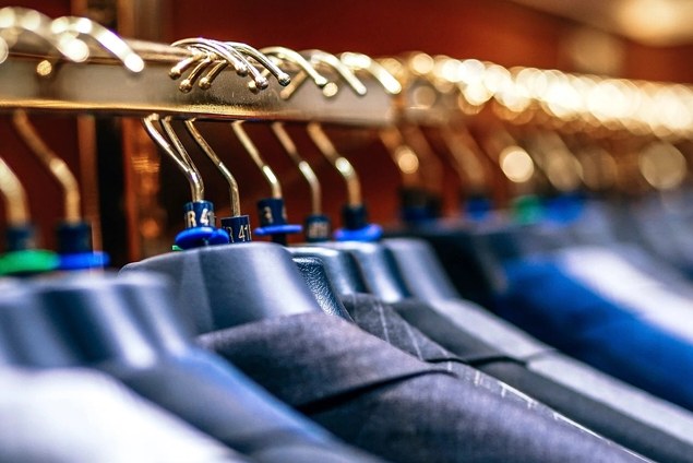 Close crop of several suit jackets on hangers, showing the shoulder area and spacing between garments