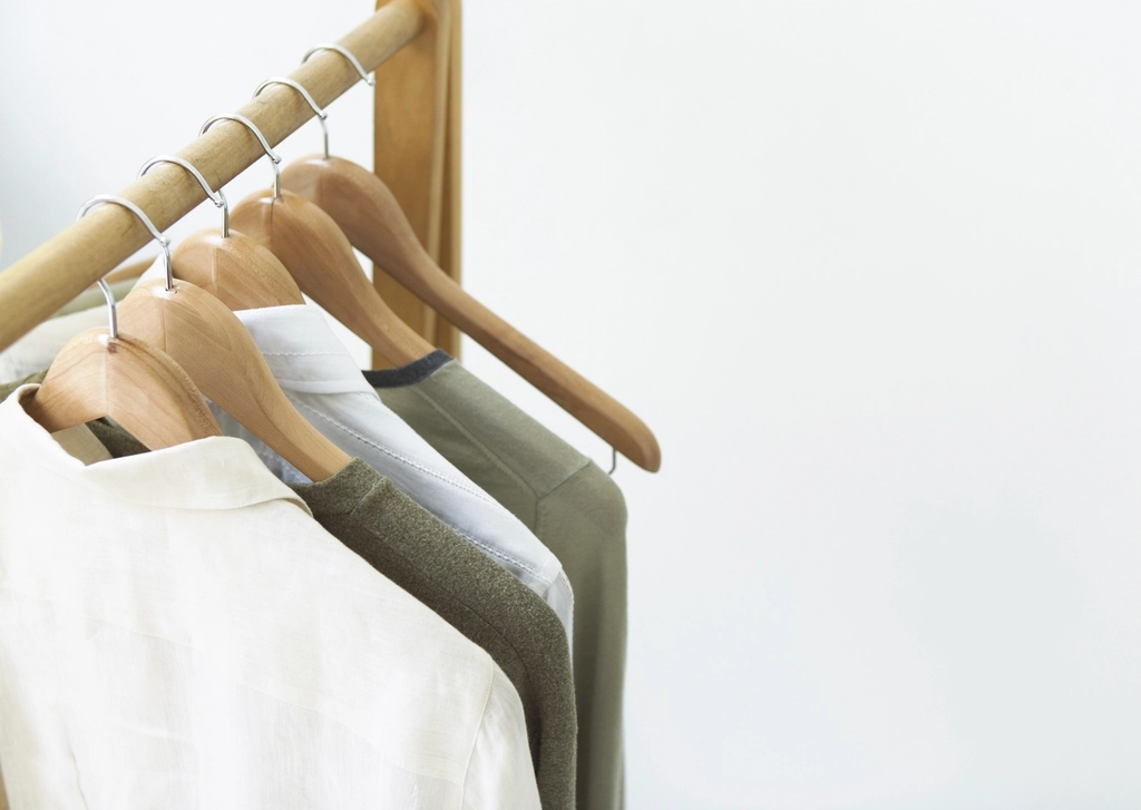 Row of dress shirts on wooden hangers in a closet, properly spaced with collars buttoned