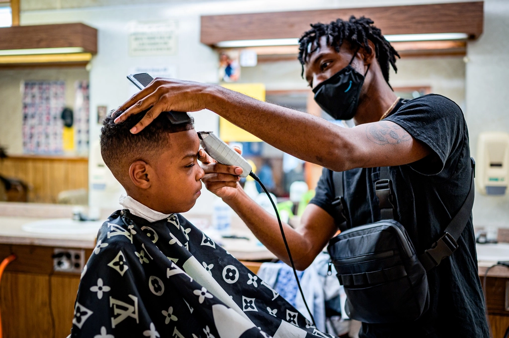 Multiple barbers cutting hair in a row of chairs — the barbershop as routine maintenance
