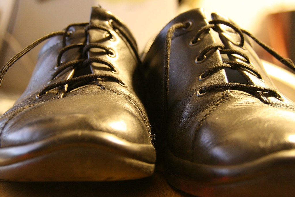 Hands applying wax polish to a dress shoe — the nourish stage