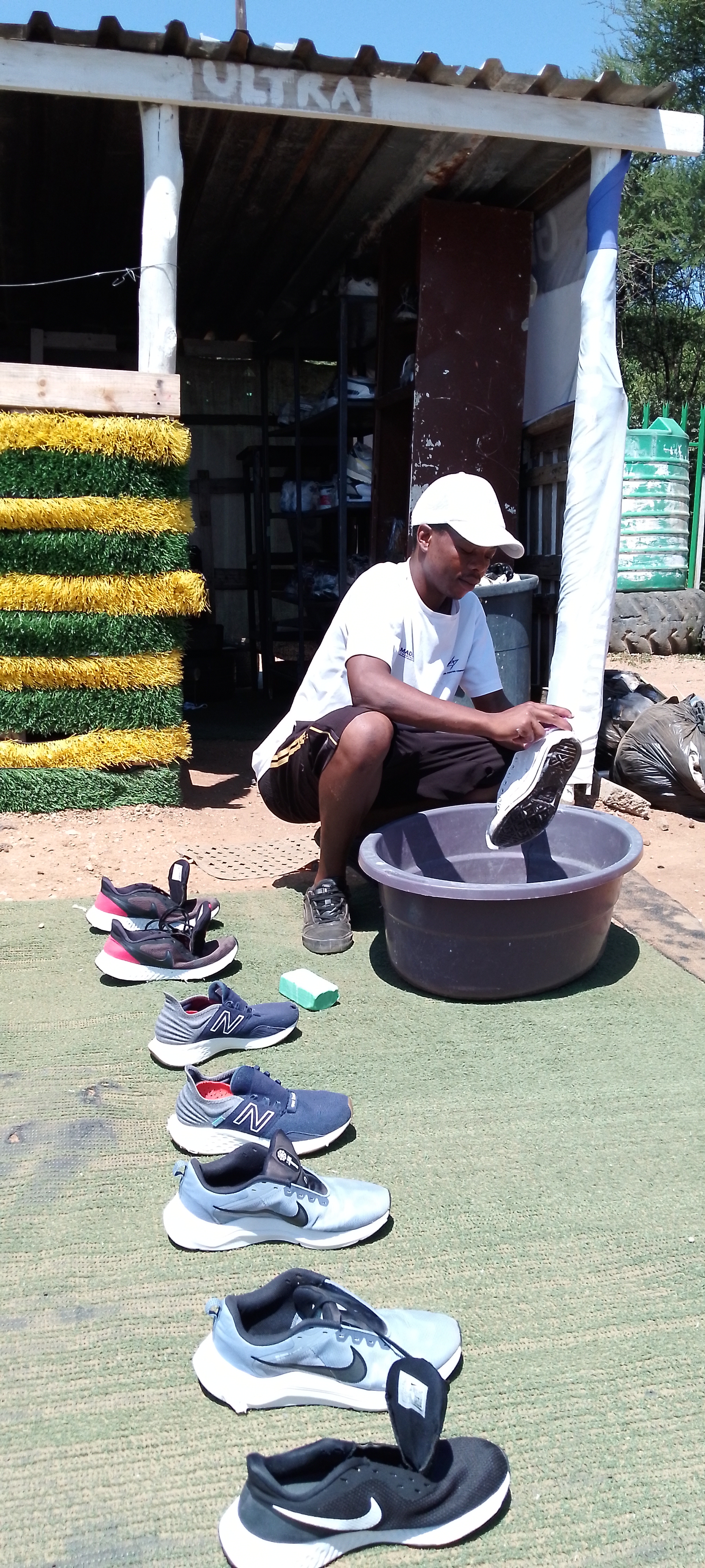 Sneakers being washed by hand with brush and water at a dedicated cleaning setup