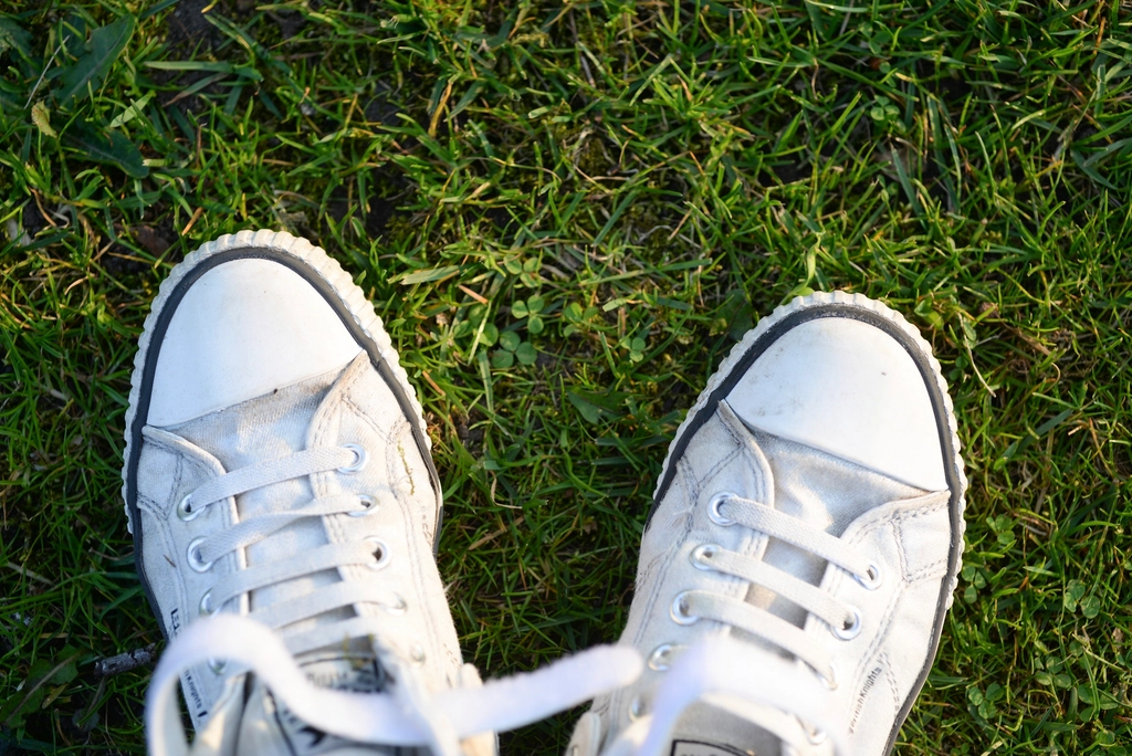Worn white canvas sneakers showing scuffed toe caps and dulled soles