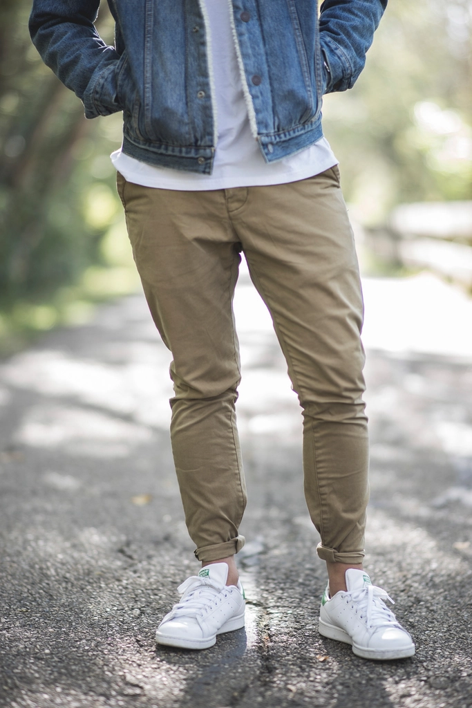 Clean white leather sneakers worn with khaki trousers and a denim jacket