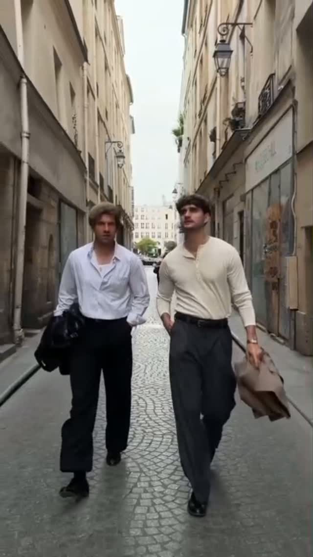 Two men in clean casual office outfits with light tops, dark trousers, and simple shoes